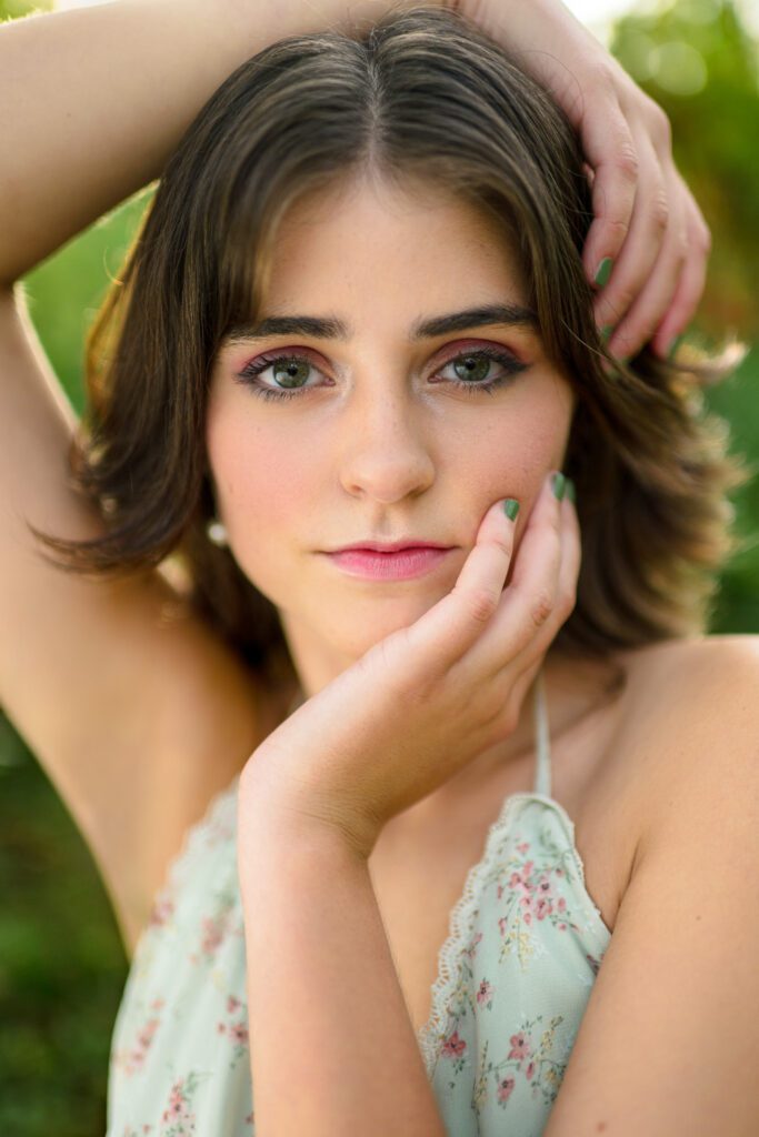 Senior girl lightly touching her face with green background