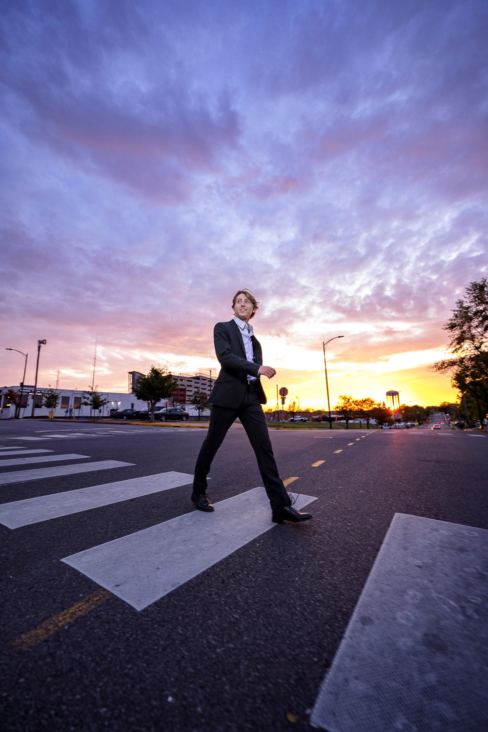 senior guy walks across cross walk during beautiful columbia missouri sunset