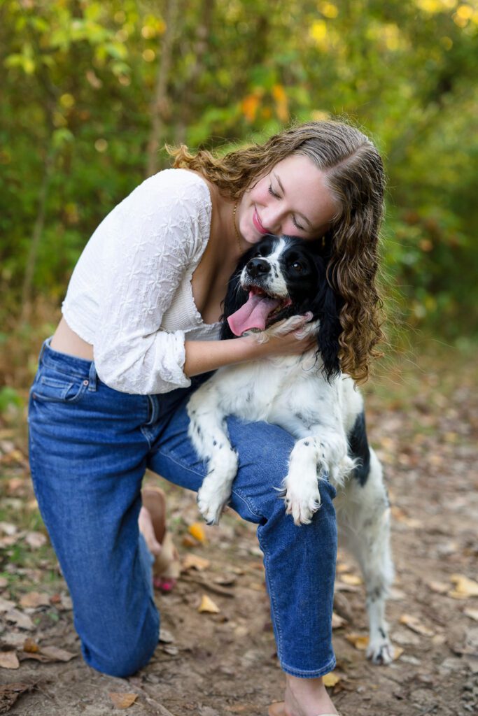 Senior girl hugs her black and white dog