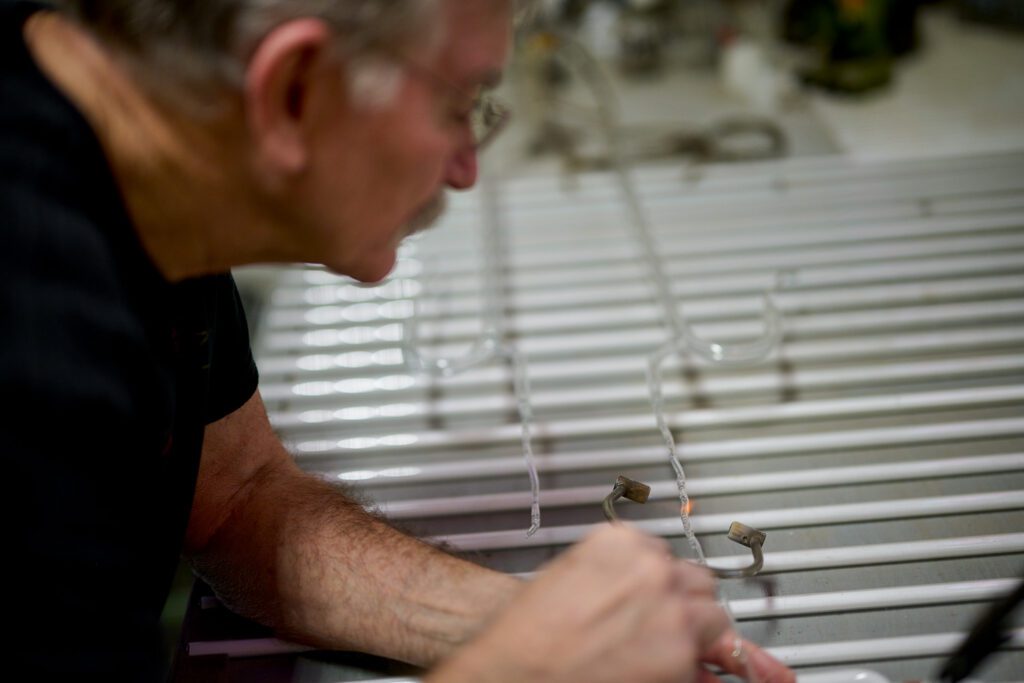 Jim McCarter uses a flame to cut glass neon tube.