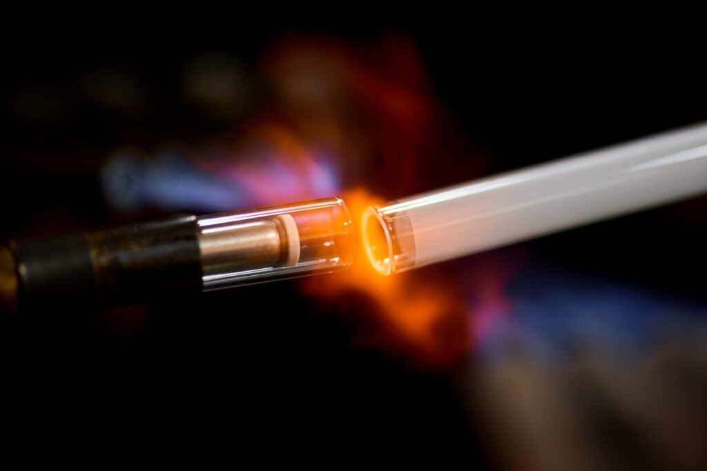 Neon glass tube and electrode up close in cross fire burner flame.