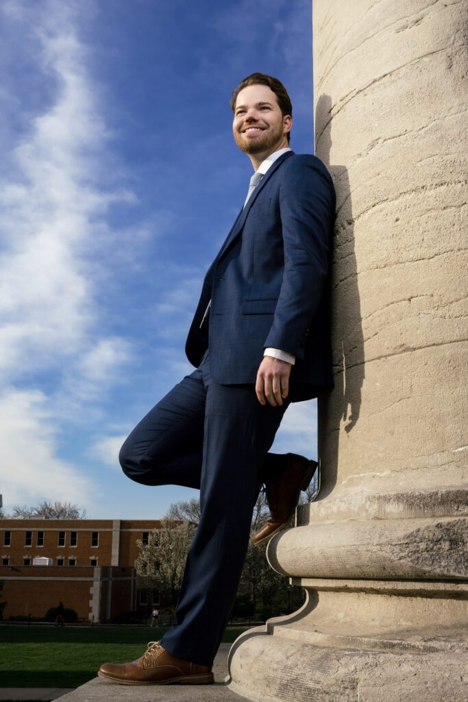 mizzou senior guy wearing suit leans on mizzou column