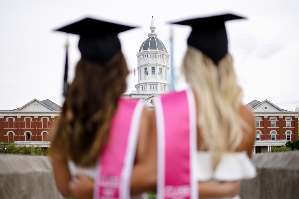 two senior women with pink stoles and mortar boards looking to jesse hall