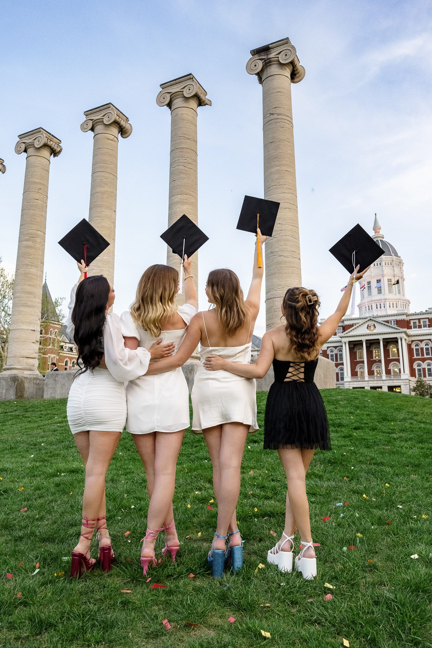 4 senior women hold graduation caps up in air mizzou columns jesse hall 
