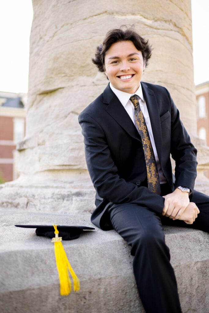 Senior guy wearing suit sitting on mizzou column