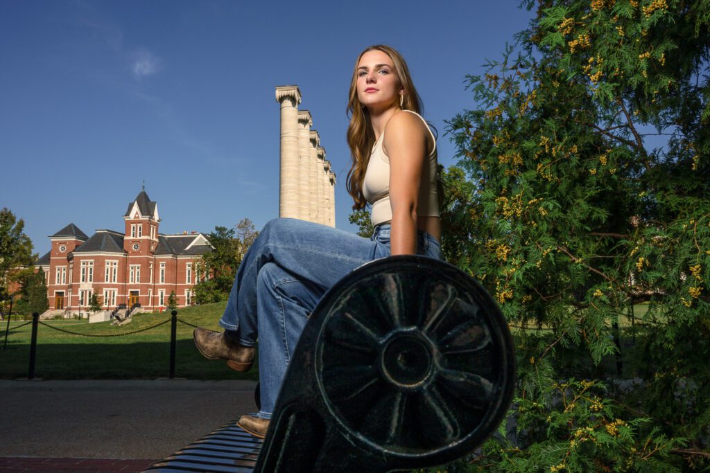 Senior girl sitting on bench with Mizzou columns