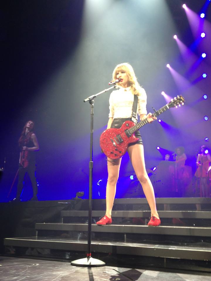 Taylor Swift holds red guitar on stage during Red Tour