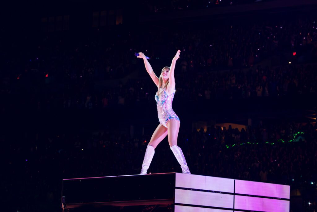 Taylor Swift dances wearing a body suit with arms in air