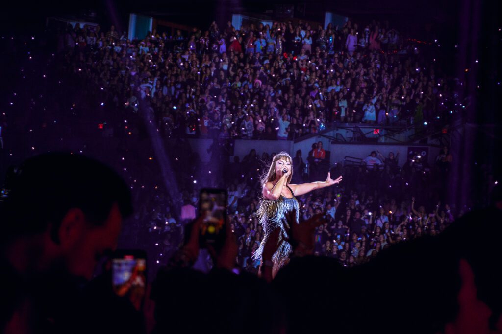 Taylor swift raises her arm as she sings in indianapolis eras tour