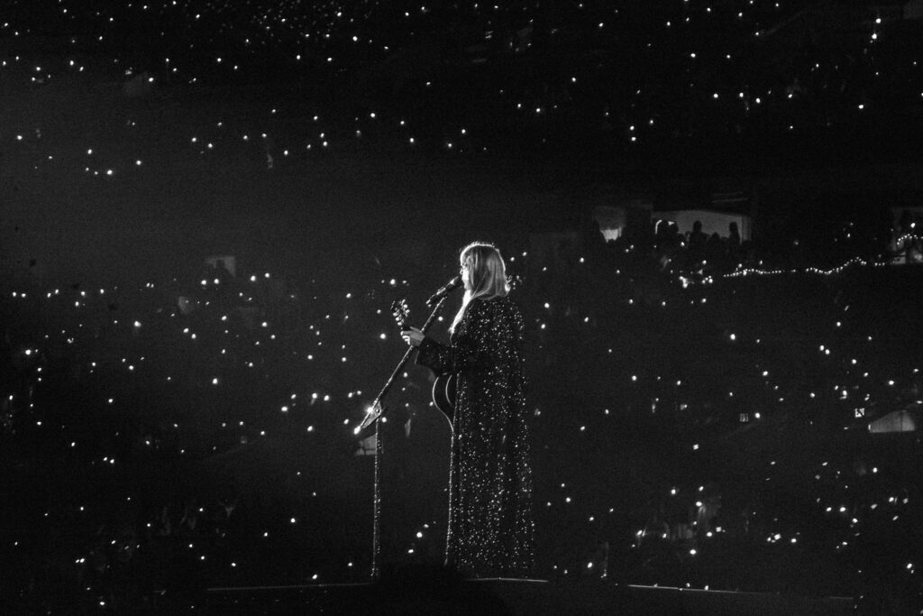 black and white image of taylor swift with lights in crowd