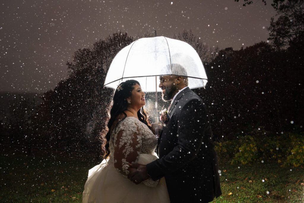 bride and groom share umbrella under rain