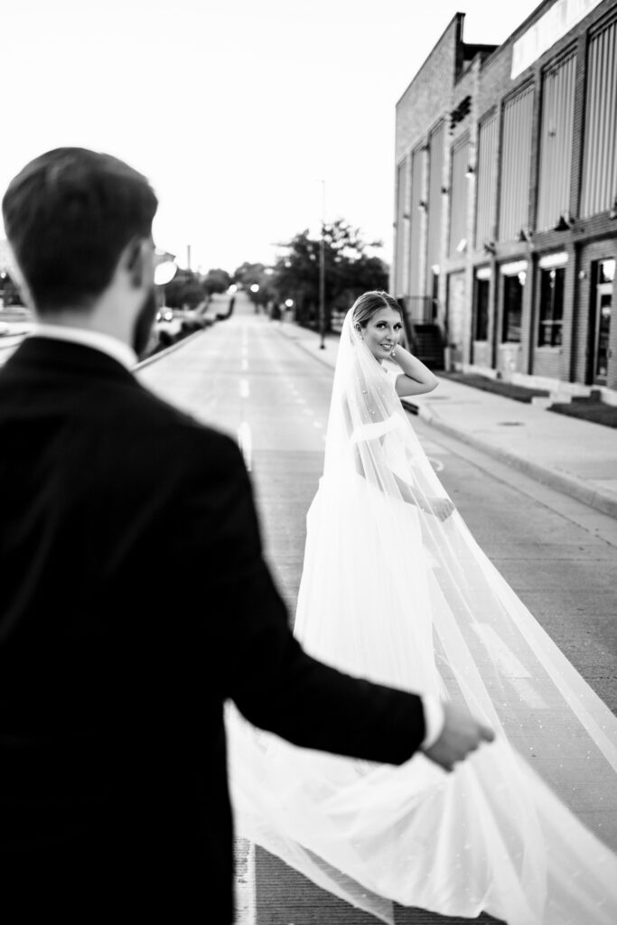 bride and groom walking in street black and white photo