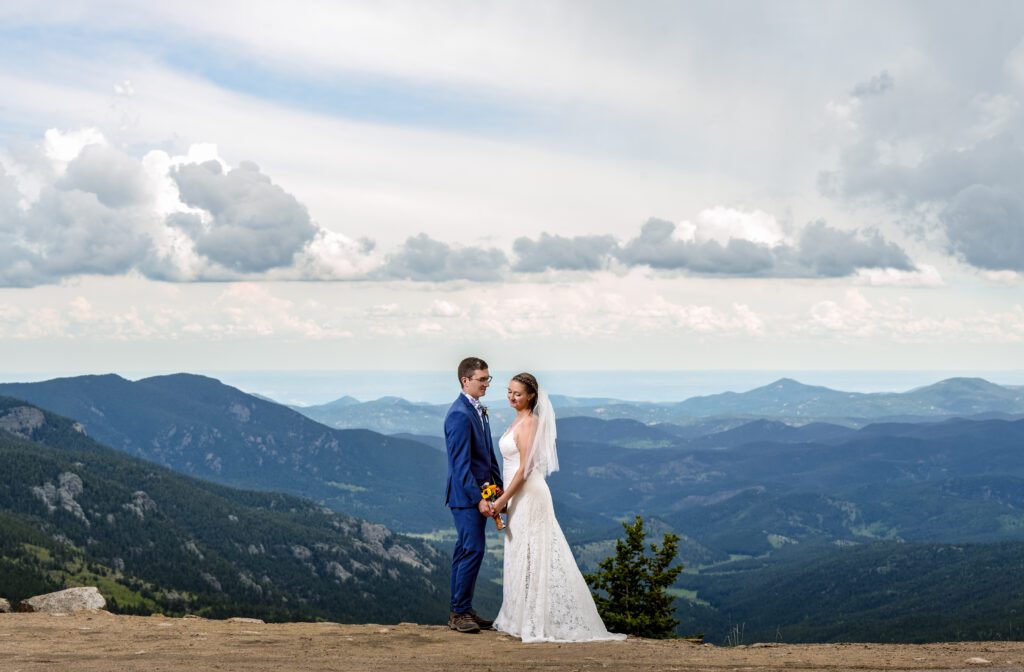 bride and groom hold hands in front of colorado mountains