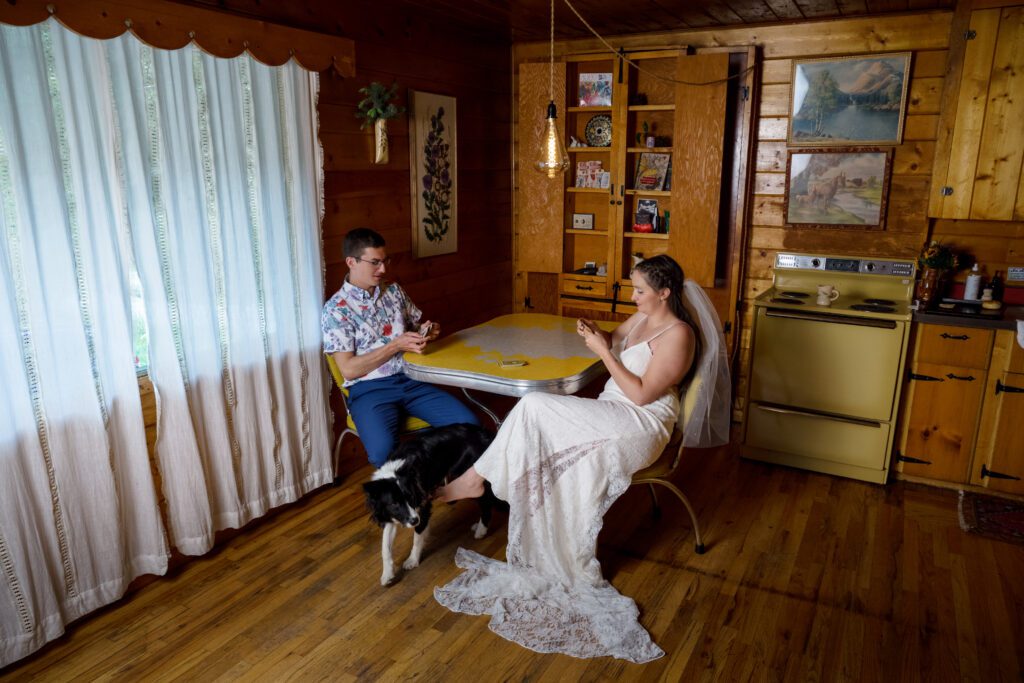 bride and groom playing cards in cabin with vintage kitchen table