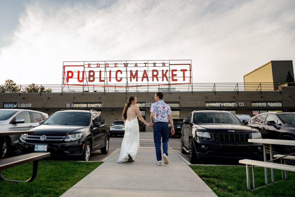 bride and groom walk towards front of colorado public market sign