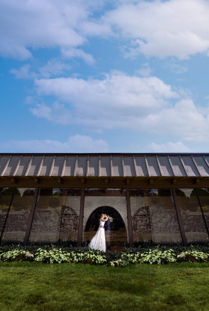 Bride and Goom wide shot buildingn with blue sky and clouds