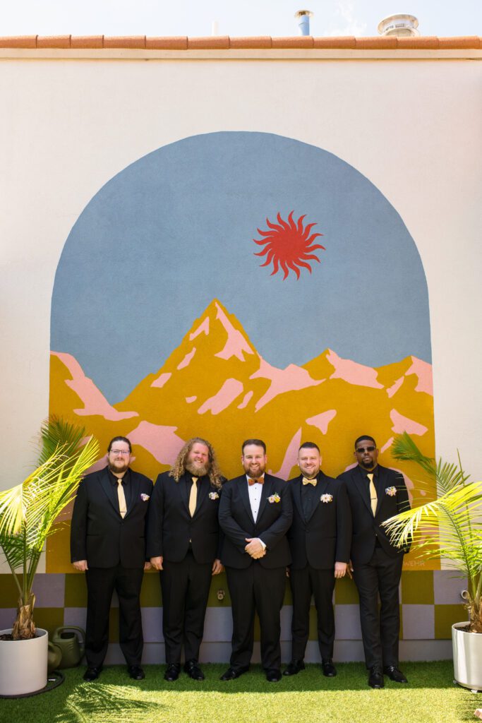 groom and groomsmen stand agains painted mountain scene on wall kansas city